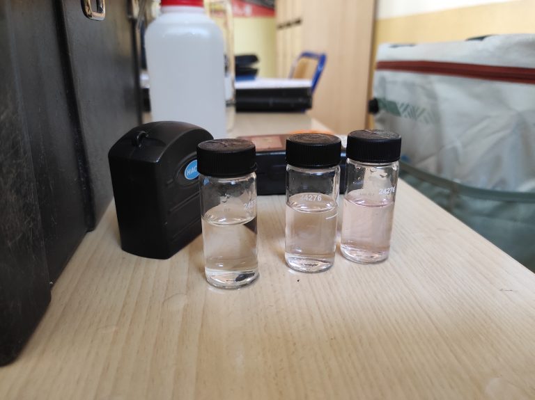 Les trois flacons pour l'analyse de l'eau sont prêts. L'eau dans deux d'entre eux se teinte en rose. | ©Le Trois - Loéva Claverie