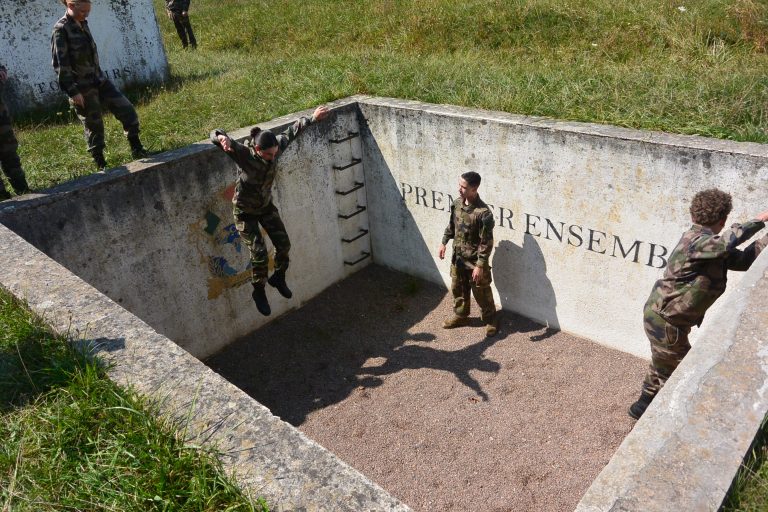La fosse: il faut sauter dedans en se réceptionnant sur les deux pieds et en fléchissant les genoux, puis ressortir sans utiliser l'échelle. Si besoin avec l'aide des copains de promo.