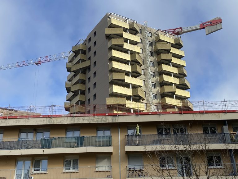 Au premier plan, l'immeuble bas en cours de rénovation, au second plan, une façade de tour rénovée.