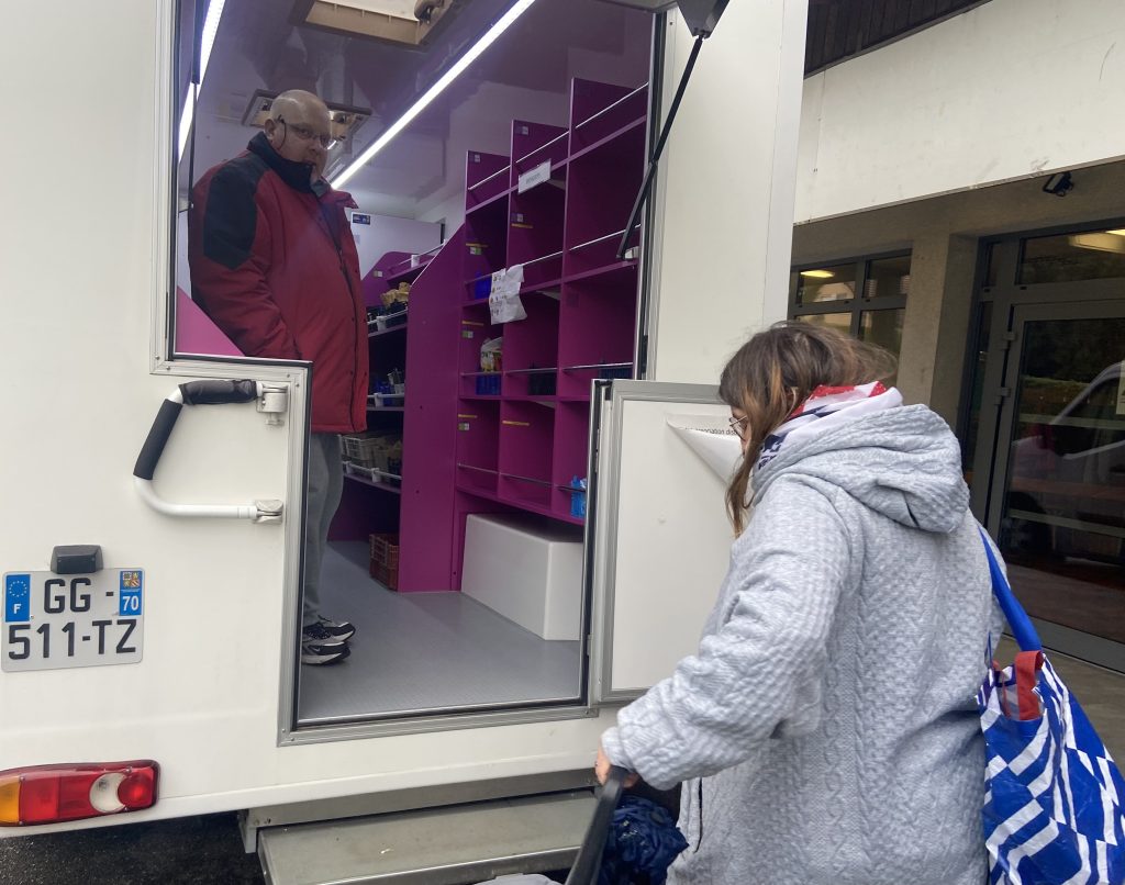 Jean-Philippe, bénévole pour les Restos du coeur, accueille une bénéficiaire dans le centre itinérant.