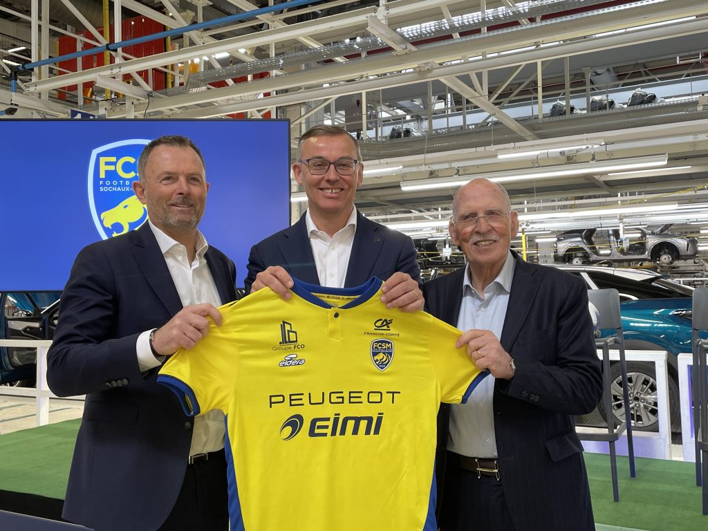 Sandro et Bartolino Nardis entourent Alain Favey, directeur général de Peugeot, avec le nouveau maillot du FC Sochaux-Montbéliard qui arbore son nouveau partenaire, le mercredi 11 mars dans l'usine Stellantis de Sochaux.