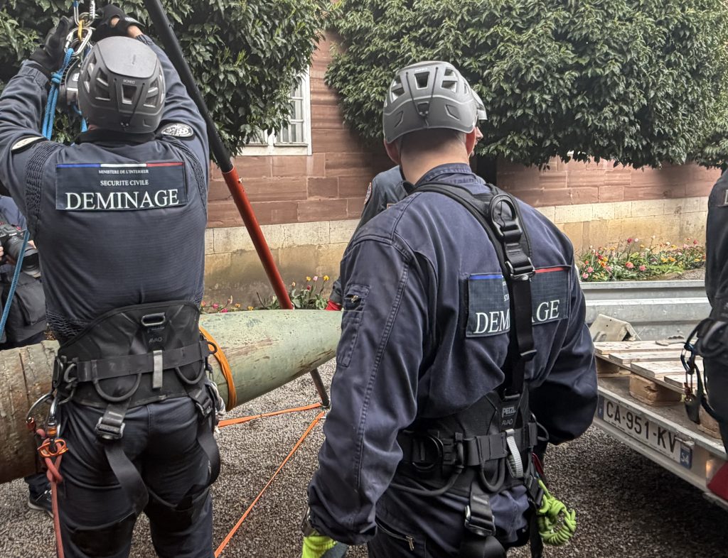 Les membres du Groupe de déminage en milieu périlleux hissent l'obus situé dans la cour d'honneur.