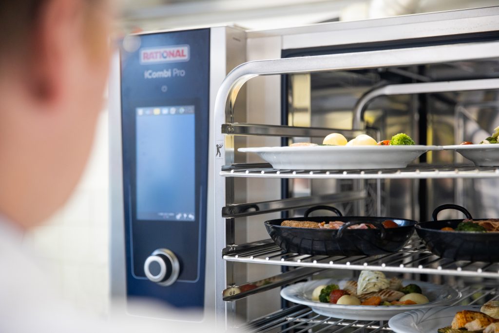 Une cuisiner plaçant des plats dans un four Rational.