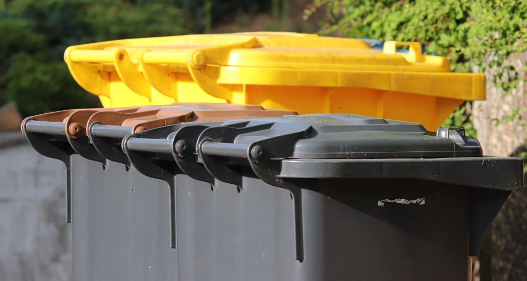 Poubelles jaunes et grises dans la rue.
