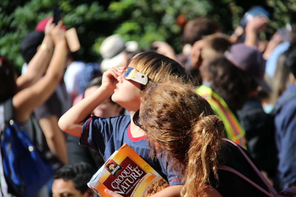 Des personnes observant une éclipse avec des lunettes.