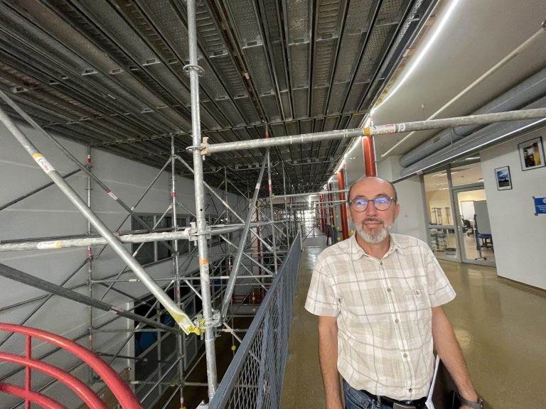 Hervé Durupt, responsable du service patrimoine de l'UTBM, devant un échafaudage monté pour le remplacement des verrières. Ils soutiennent une plateforme étanche à l'air et à la poussière.