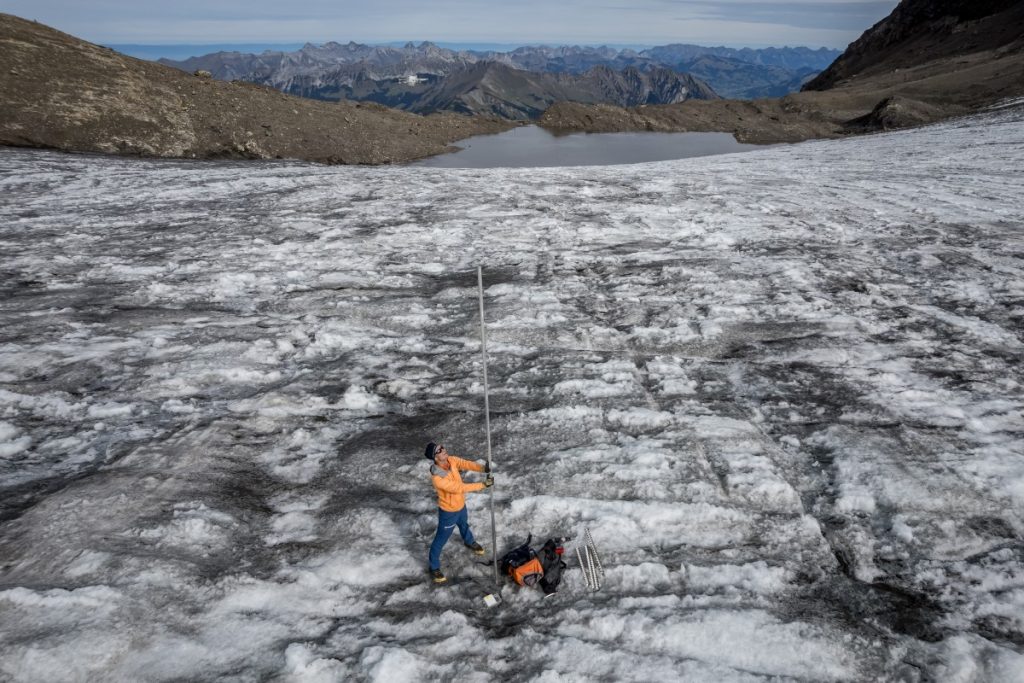 Cette photo aérienne montre le glaciologue suisse Matthias Huss, qui pose avec une tige de 4 mètres de long qui indique la hauteur de glace qui a fondu cette année, au glacier du Scex rouge, au-dessus des Diablerets, à l'ouest de la Suisse, le 24 septembre 2026.