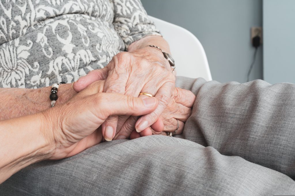 les main d'une personne âgée et d'un accompagnent.